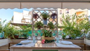 A table set outdoors with a white tablecloth, a wine bottle, and potted plants. - Apartment 'Casa Cordemar Alghero' with Private Terrace, Wi-Fi and Air Conditioning (Alghero)