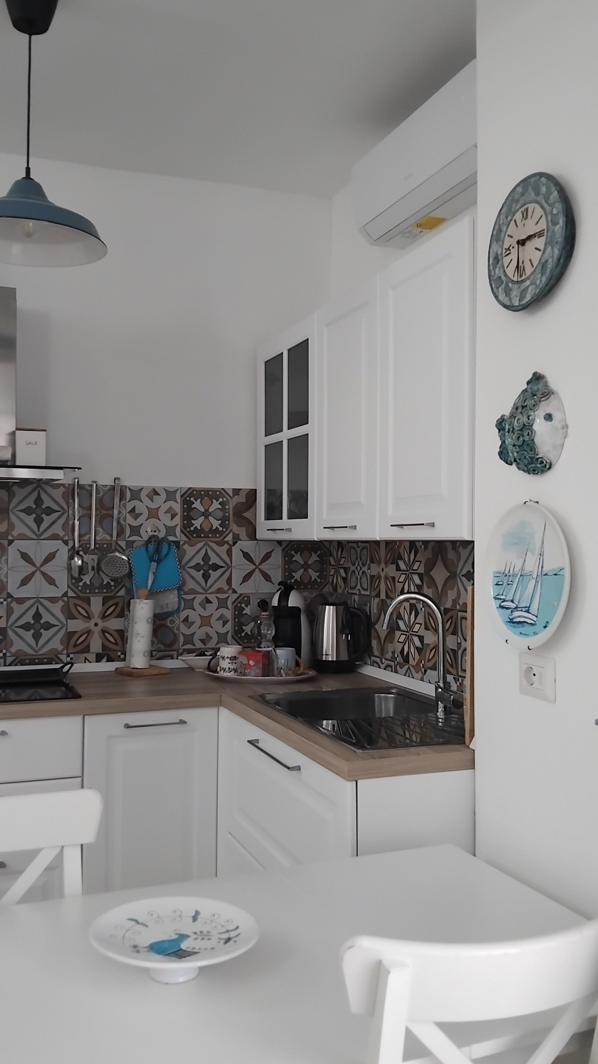 A kitchen with white cabinets, a sink, a stove, and a dining area with a white table and chairs.