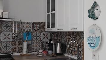 A kitchen with white cabinets, a sink, a stove, and a dining area with a white table and chairs.