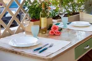 Una mesa de comedor dispuesta con platos, cubiertos, una botella de vino y un florero con flores.