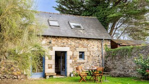 A stone cottage with a small garden, a wooden table with chairs, and a blue door. - Holiday Home 'Ville Daniel' with Private Terrace, Private Garden and Wi-Fi (PORDIC)