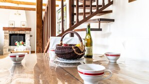 A wooden table with a wicker basket, a bottle, and white cups with red stripes. - Holiday Home 'Ville Daniel' with Private Terrace, Private Garden and Wi-Fi (PORDIC)
