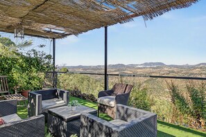 Un área de estar exterior con muebles de mimbre y vistas al campo.
