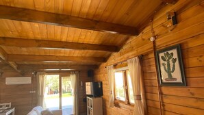 A wooden cabin interior with a sofa, chairs, a TV, and a framed picture on the wall. - Holiday Home 'Miralvalle' with Mountain View, Wi-Fi and Air Conditioning (El Gastor)