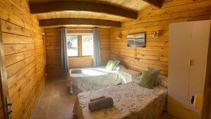 A cozy cabin room with wooden walls, a bed, a small table, and a wardrobe. - Holiday Home 'Miralvalle' with Mountain View, Wi-Fi and Air Conditioning (El Gastor)