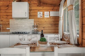 A wooden interior with a kitchen area, a dining table set with plates, glasses, and cutlery, and a bottle of wine on the table. - Holiday Home 'Miralvalle' with Mountain View, Wi-Fi and Air Conditioning (El Gastor)
