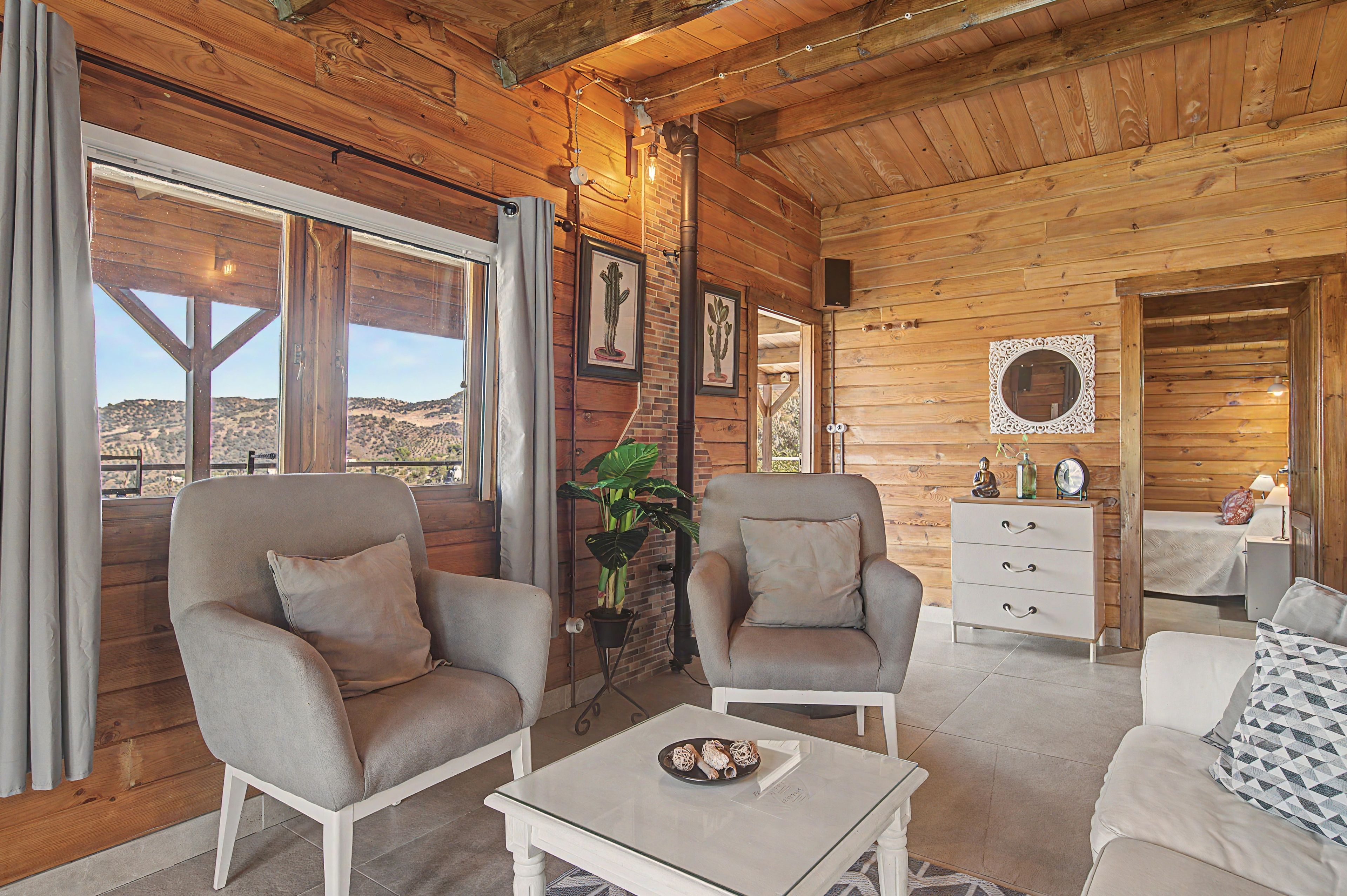L’intérieur d’une cabane en rondins, avec deux fauteuils, une petite table, une commode et un miroir.