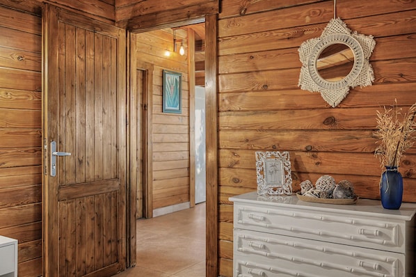 Un interior de madera con un aparador blanco, un colgador decorativo de macramé y un cuadro enmarcado.