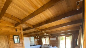 A spacious living area with a wooden ceiling, a kitchen, and a dining area with white furniture. - Holiday Home 'Miralvalle' with Mountain View, Wi-Fi and Air Conditioning (El Gastor)