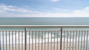 A beach view from a balcony with a railing, ocean waves, and a clear sky. - Sunset Retreat: Two Bdrm Oceanfront 15th Floor (Myrtle Beach)