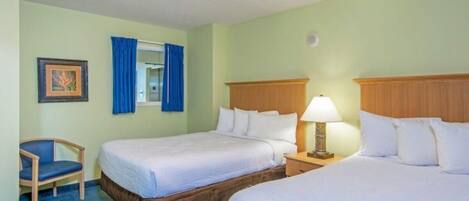 Habitación de hotel con dos camas, una silla, un ventanal con cortinas azules y un cuadro enmarcado en la pared.