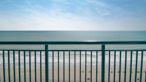 Blick auf einen Strand mit einem Metallgeländer im Vordergrund.