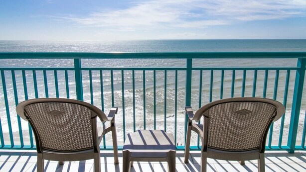 A balcony with two wicker chairs and a small table, overlooking the ocean. - Oceanfront 3 BR Condo Amazing Views 14th floor! (Myrtle Beach)