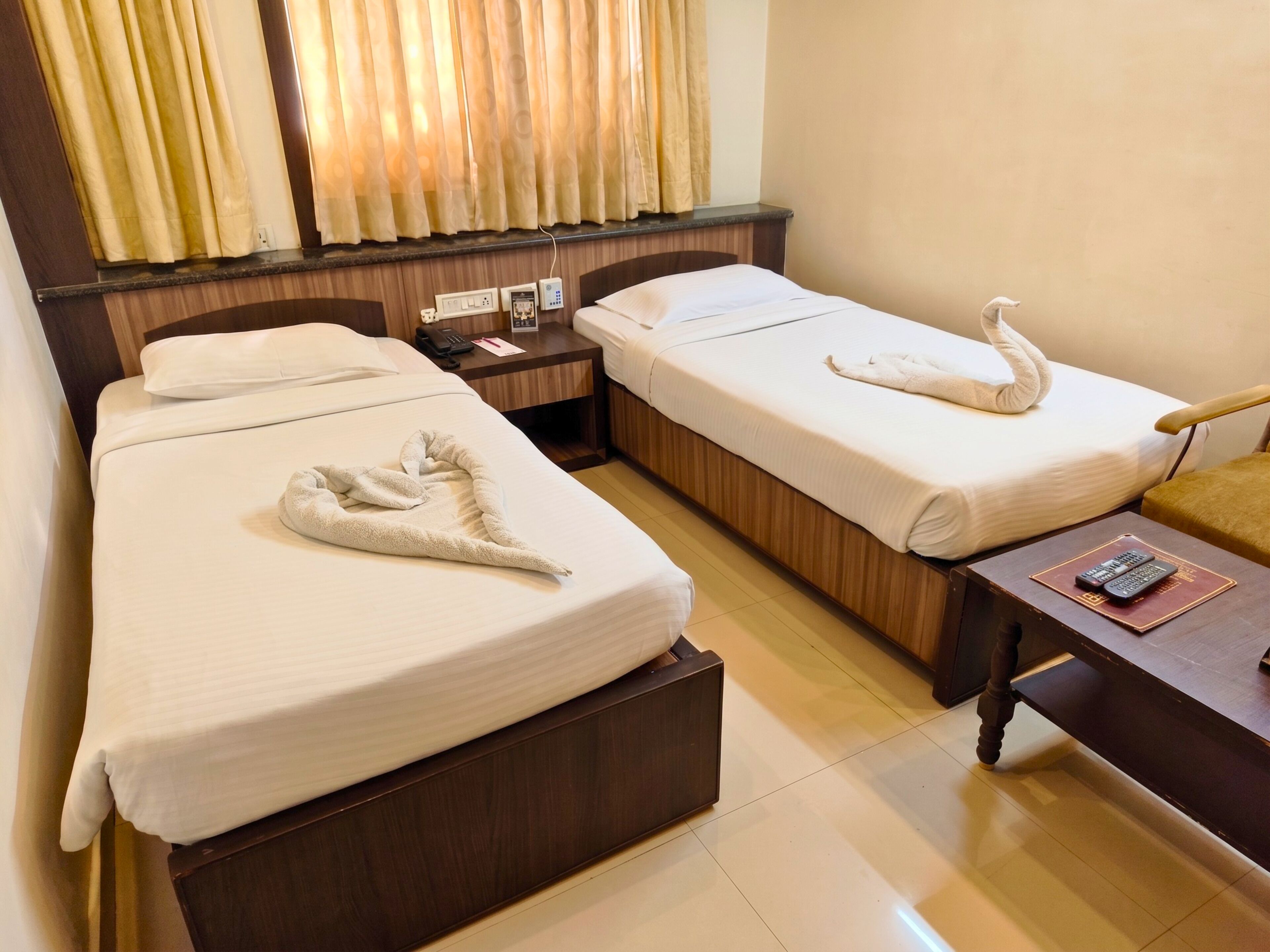 A hotel room with two beds, a nightstand, a desk, and a chair.