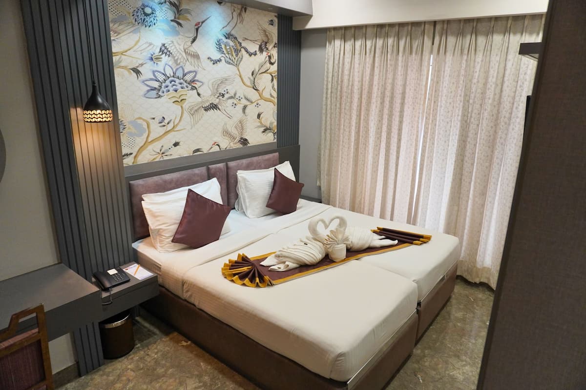 Habitación de hotel con una cama, un escritorio, un teléfono y una pared con papel tapiz floral.