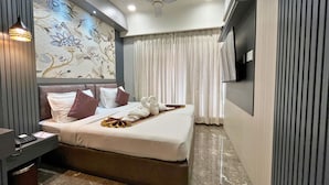 A hotel room with a bed, a desk, a telephone, a television, and a ceiling fan. - continental lodge  (Malda)