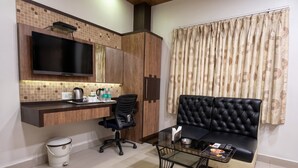 A compact living space with a kitchenette, a flat-screen TV, a sofa, and a glass coffee table. - continental lodge  (Malda)