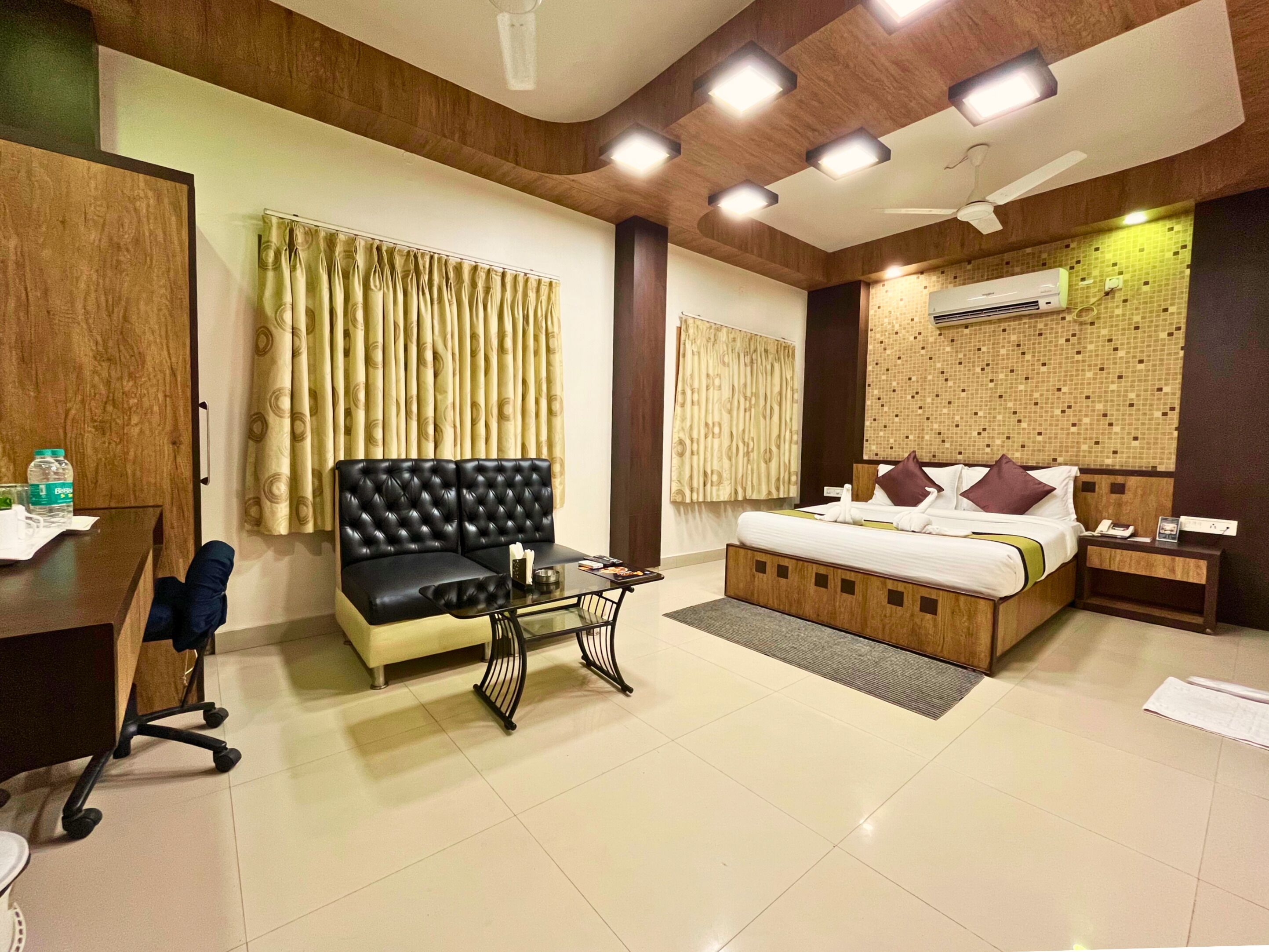 Una habitación de hotel con cama, sofá, escritorio y aire acondicionado.