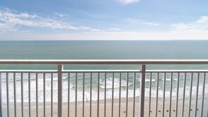 A beach view from a balcony with a railing, ocean waves, and a clear sky. - Elegant Oceanfront 1 BR Dlx Condo 15th Floor (Myrtle Beach)