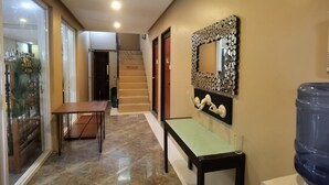 A hallway with a marble floor, a wooden bench, a wall-mounted decorative mirror, and a water dispenser. - Sunny Day Residences Cainta (Cainta)
