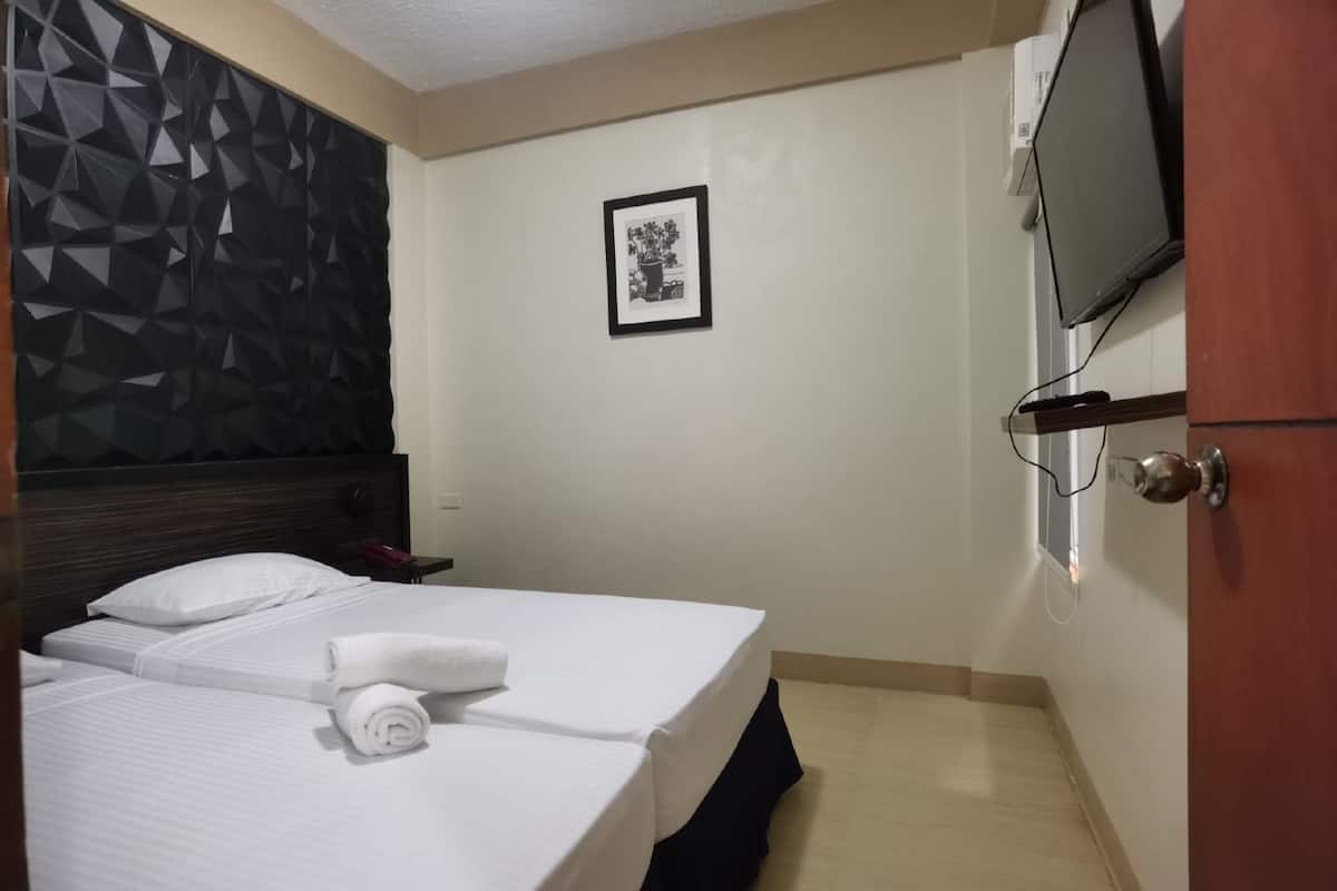 A hotel room with two beds, a TV mounted on the wall, and a framed picture on the wall.