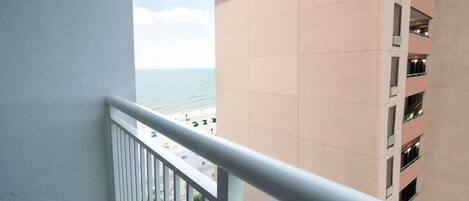 A balcony with a view of the beach and ocean.