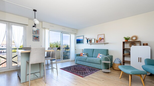 A modern living room with a sofa, a dining area, and a view through large windows. - Apartment 'Appart Anglet' with Private Terrace (Anglet)