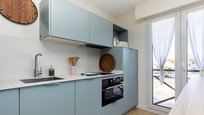 A kitchen with a sink, stove, and a clock on the wall. - Apartment 'Appart Anglet' with Private Terrace (Anglet)