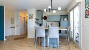 A modern kitchen with a dining area, featuring a wooden table, grey chairs, and a pendant light. - Apartment 'Appart Anglet' with Private Terrace (Anglet)