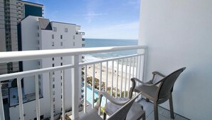 A balcony with a view of the beach and ocean, white railing, and two wicker chairs. - Oceanview Room  2 Queen Beds: 11th Floor (Myrtle Beach)