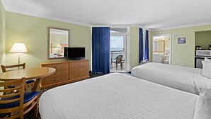 Une chambre d’hôtel avec deux lits, un bureau avec une chaise, une télévision, une commode et un balcon avec vue.