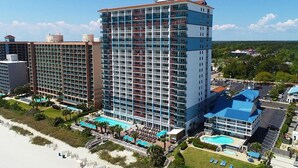 A high-rise hotel with multiple balconies, a pool area, and a beach view. - Partial Oceanview Room  2 Queen Beds 9th Floor (Myrtle Beach)