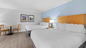 A hotel room with two beds, a small table with chairs, and two framed pictures on the wall. - Partial Oceanview Room  2 Queen Beds 9th Floor (Myrtle Beach)