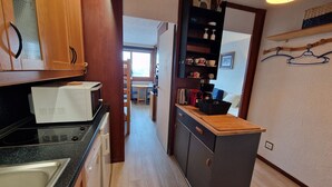 Una cucina compatta con forno a microonde, lavello e piano di lavoro in legno. Sullo sfondo, è visibile un'area pranzo.