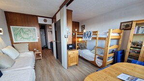 Una camera compatta con un letto a castello, una scrivania, una sedia e una libreria.