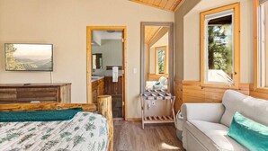 A cozy room with a bed, a sofa, a TV, and a wooden ceiling. - * Snowy Evening Lodge * / Treetop Views & Firepit (Big Bear)