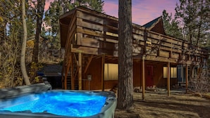 A wooden cabin with a hot tub and a covered porch.