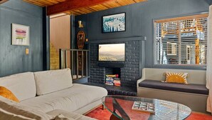 A modern living room with a fireplace, a sofa, a coffee table, and a large window with blinds.