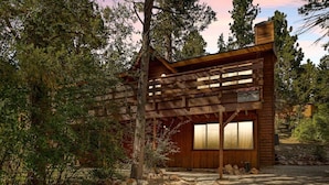 A rustic cabin with a wooden exterior, large windows, and a stone foundation.