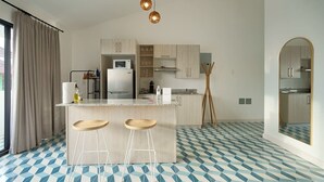 A modern kitchen with a central island, bar stools, and pendant lighting.