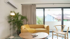 A modern living room with a sofa, a round wooden table, a floor lamp, and a chair.