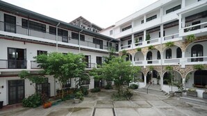 A courtyard with a central open space surrounded by multi-level buildings with balconies and potted plants.