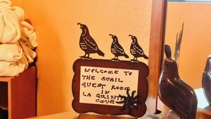 A welcome sign with a bird decoration and a towel stack. - Quail Befroom  (La Quinta)