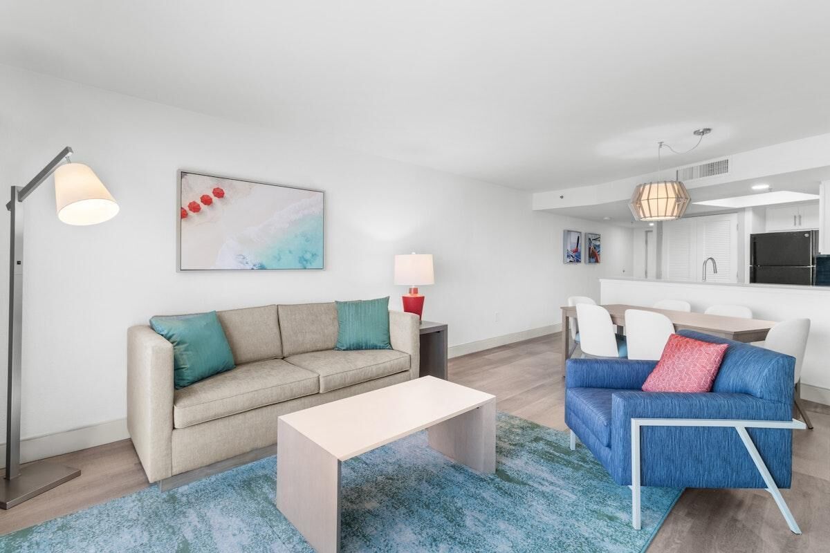 A modern living room with a beige sofa, a blue sofa, a white coffee table, and a floor lamp.