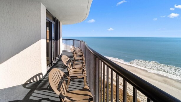 A balcony with chairs facing the ocean, a railing, and a clear view of the beach and sea. - 14th Floor Oceanfront Corner Balcony 2BR Condo (Myrtle Beach)