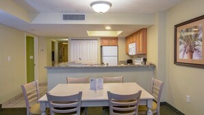 A compact kitchen with a dining area, featuring a white table and chairs, a microwave, and a refrigerator. - Brilliant Oceanfront 12th Floor 3BR Condo (Myrtle Beach)