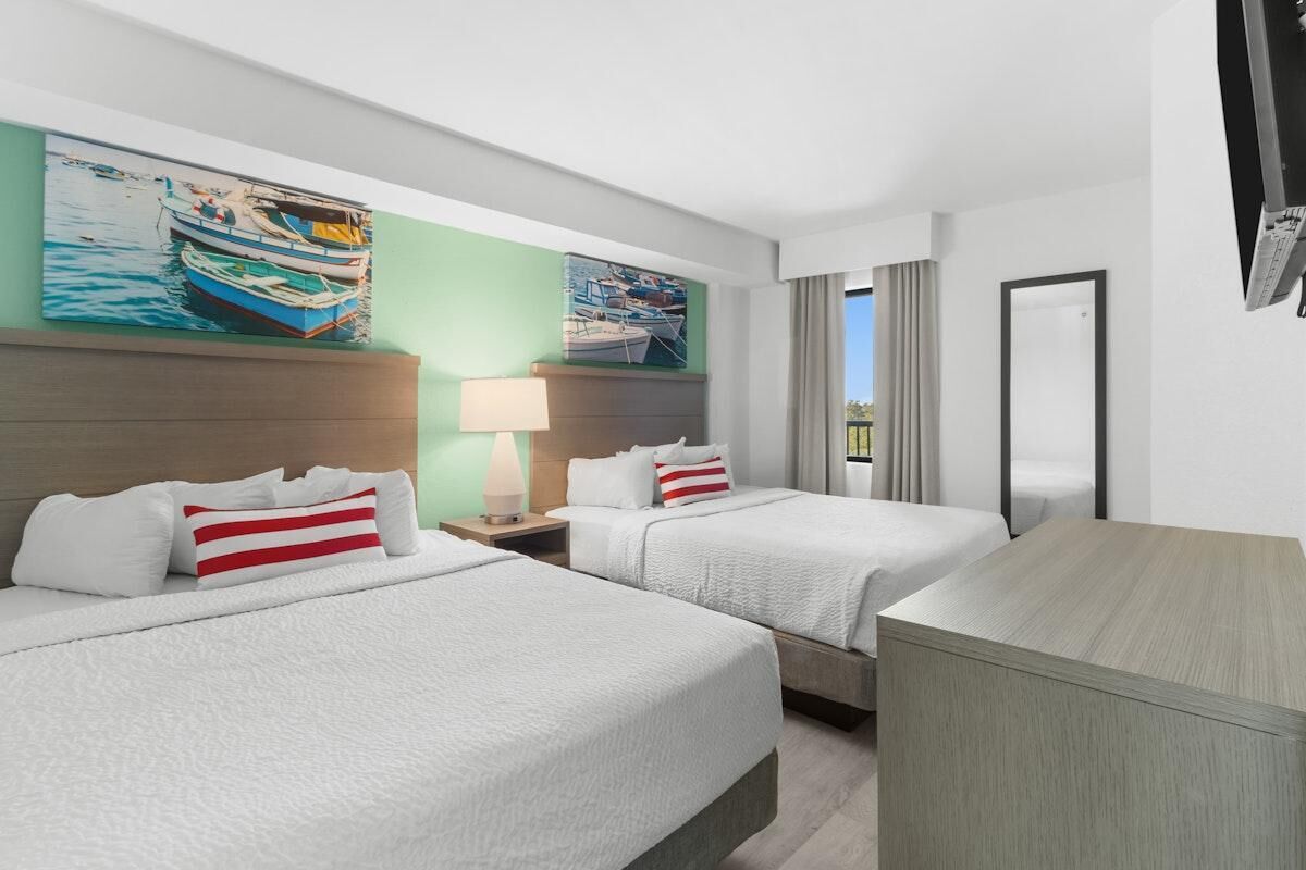 Een hotelkamer met twee bedden, een bureau, een televisie en kunst aan de muur.