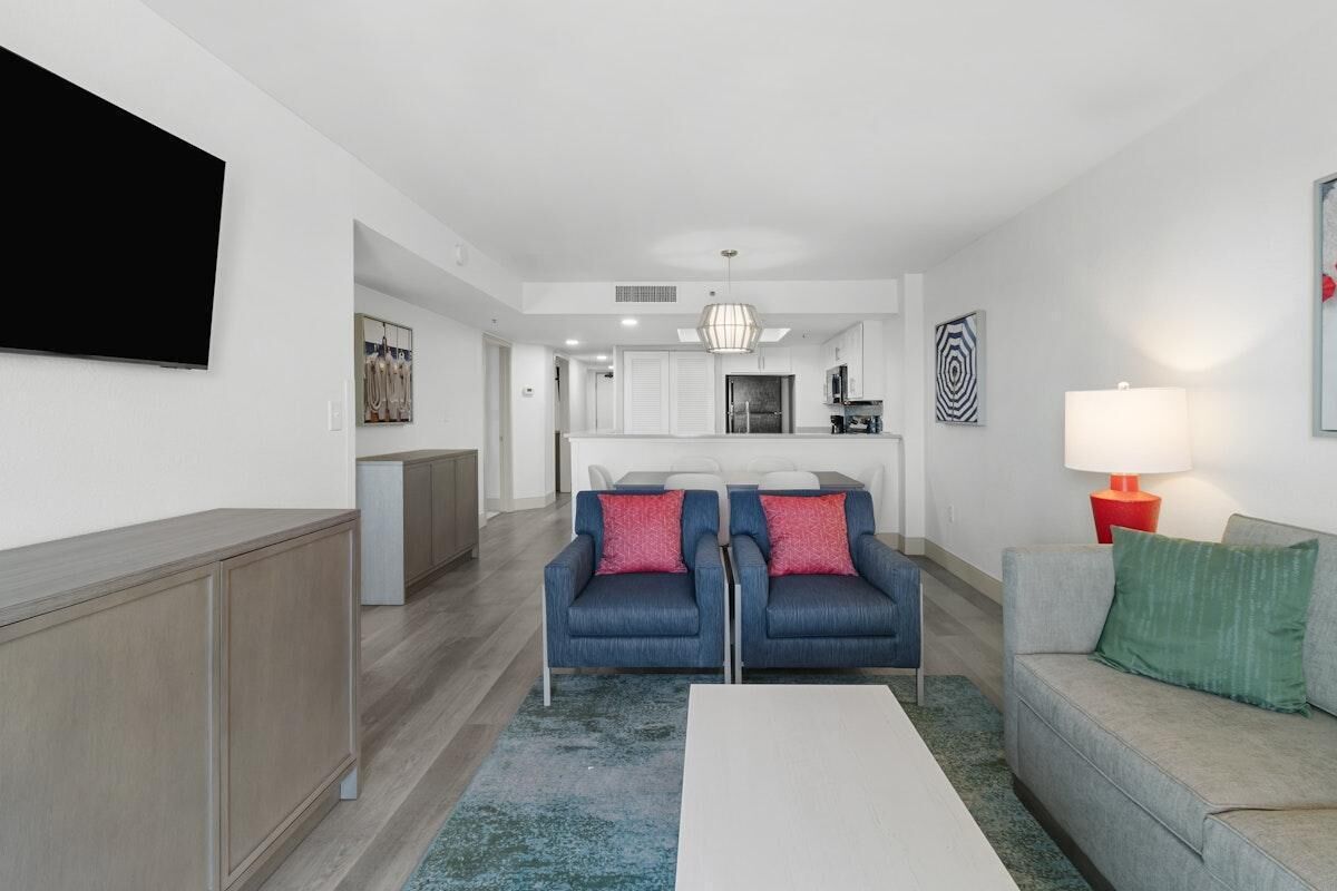 A modern living room with a sofa set, a coffee table, and a TV mounted on the wall.