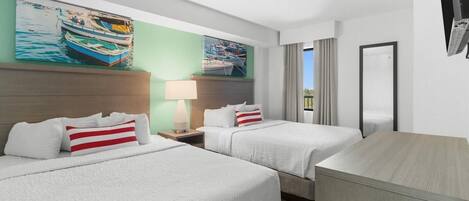 A hotel room with two beds, a desk, a TV, and artwork on the wall.