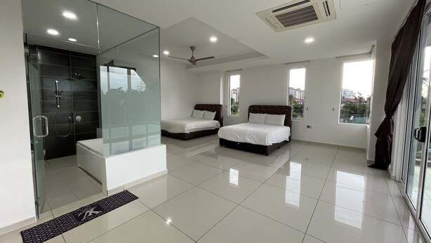 A modern bedroom with a glass shower enclosure, a large bed, and a separate sofa. - Alpine PD Taman Kiara 2 Homestay (Port Dickson)